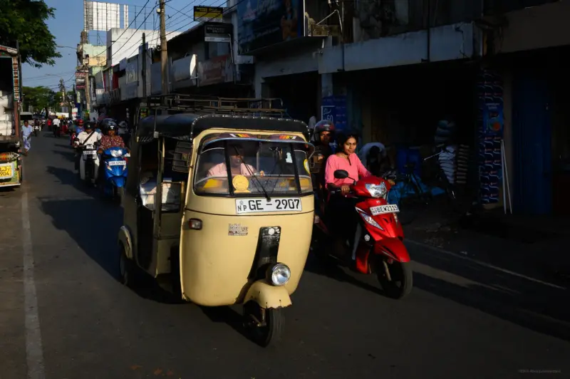 A girl riding a red scooter and a tuk tuk - Jaffna, Sri Lanka