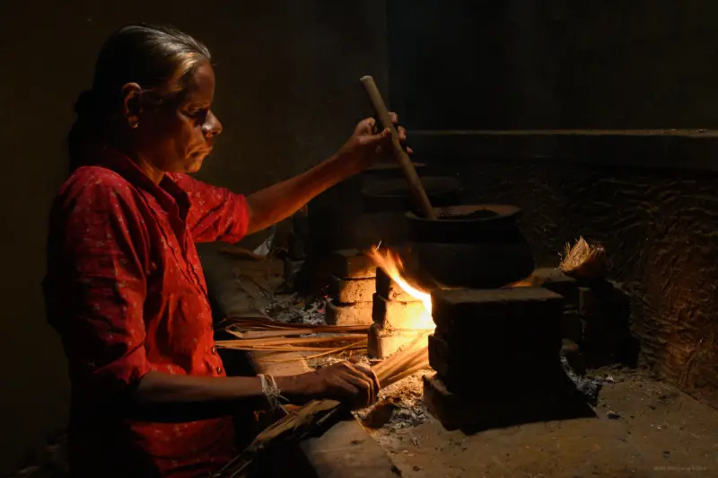A woman in a red top brewing a traditional Ayurvedic Concoction - Sri Lanka
