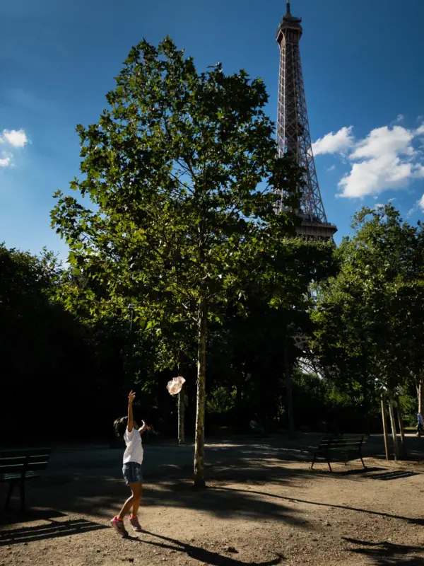 A child reaching for the wind blown hat in front of the Eiffel Tower - Paris, France